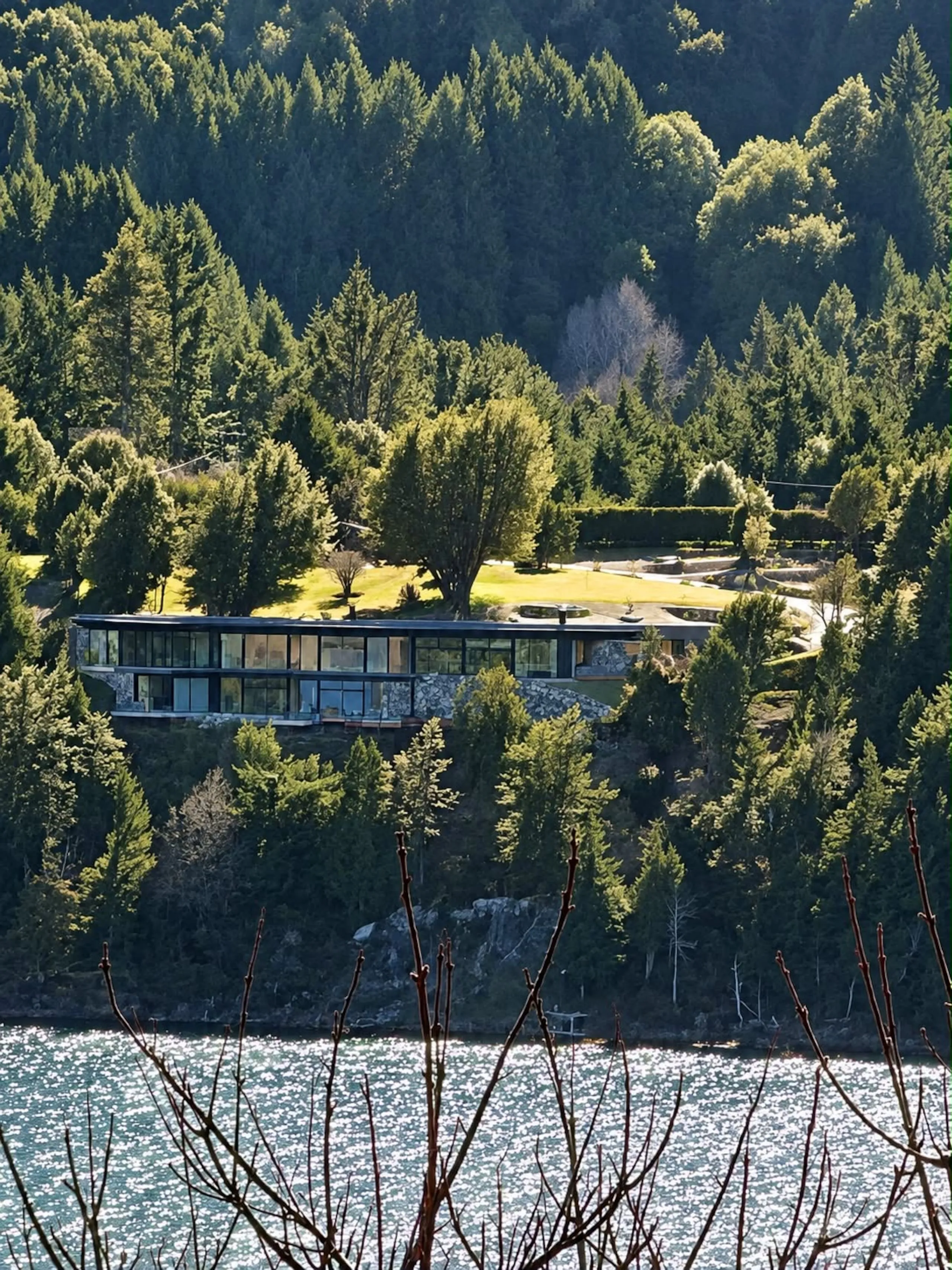 La casa vidriada vista a lo lejos entre el bosque, sobre el lago