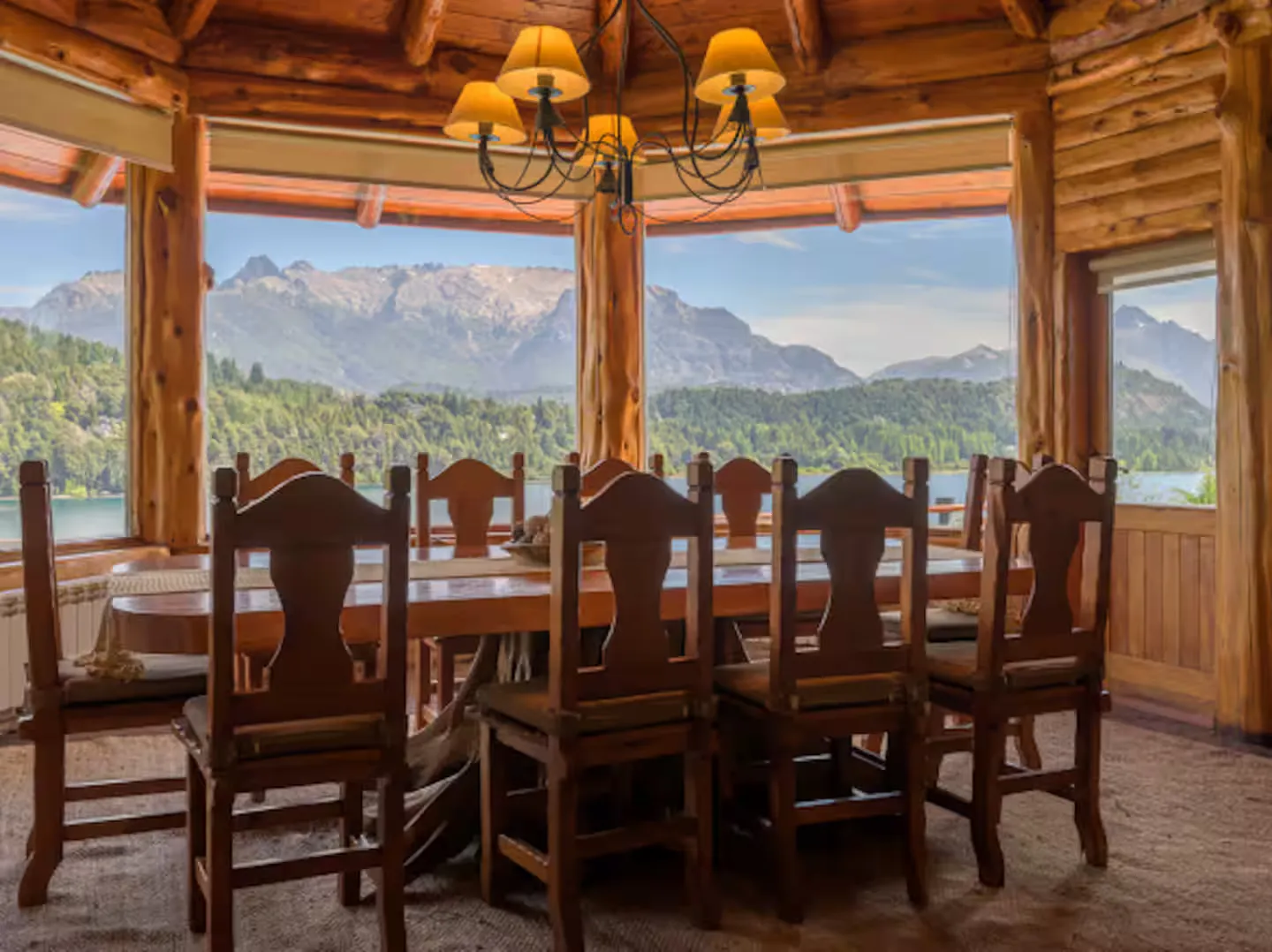 Comedor octogonal de madera con ventanales hacia el lago y la montaña