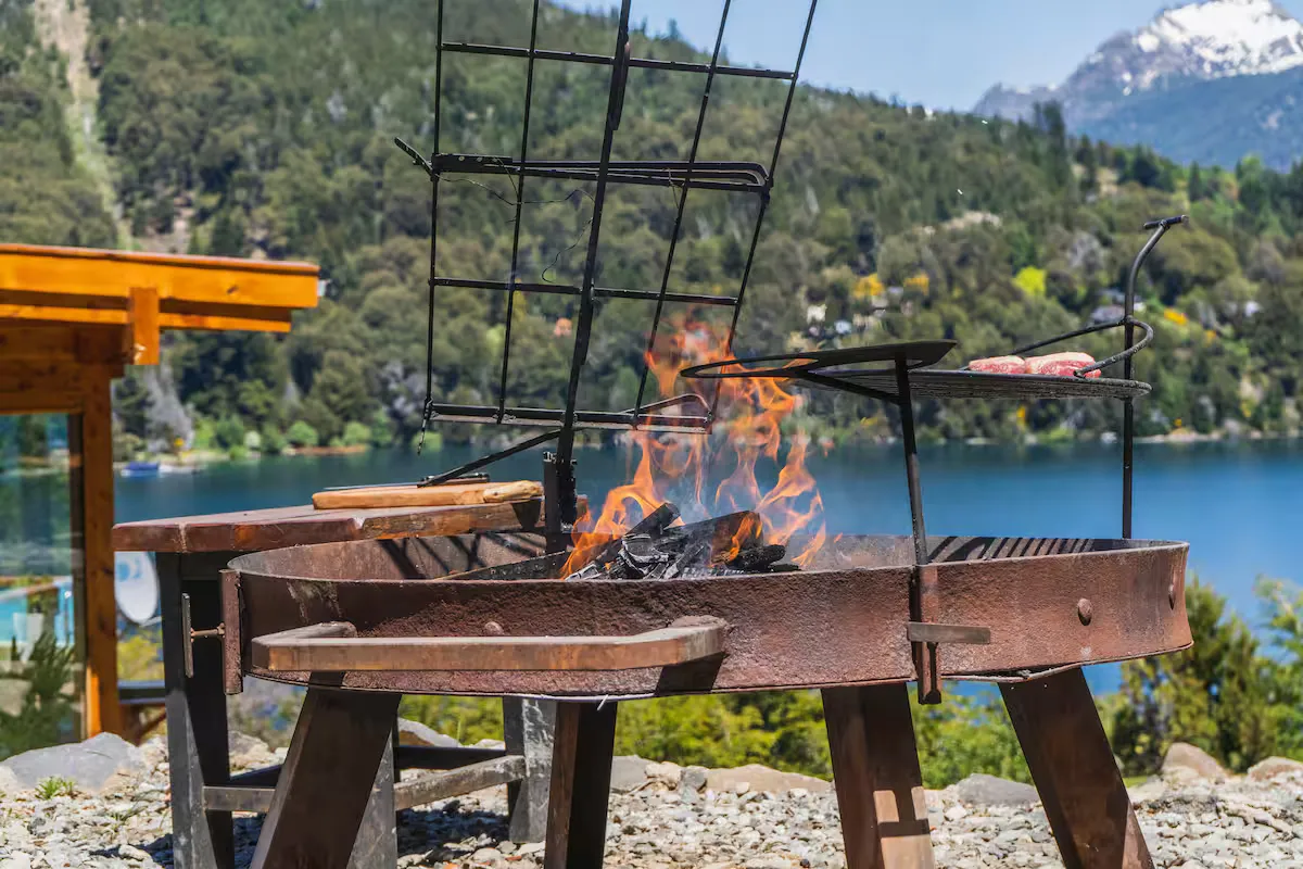 Parrilla encendida con el lago y los cerros de fondo