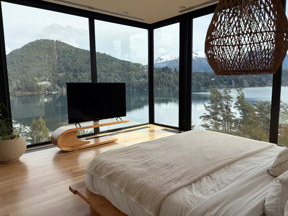 Dormitorio con cama doble y ventanales en esquina hacia el lago y el cerro
