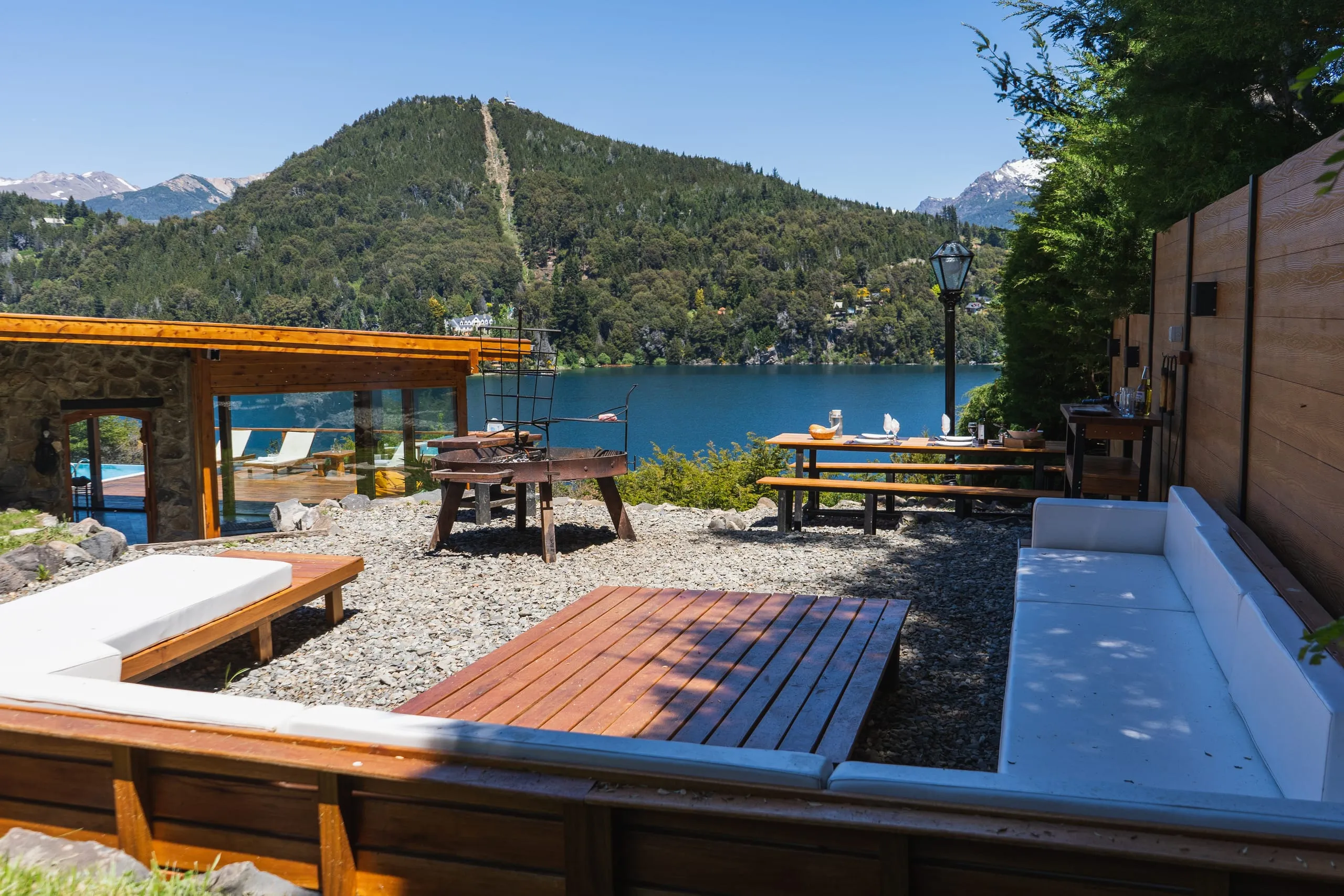 Patio con fogonero y mesas de madera sobre el lago