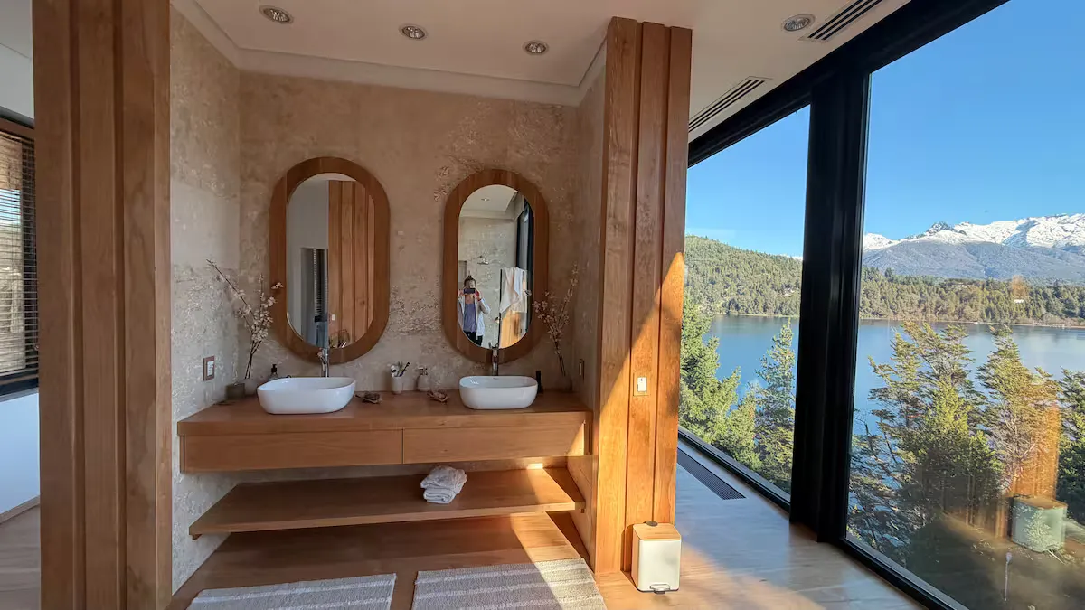 Baño con doble bacha, espejos ovalados y ventanal al lago